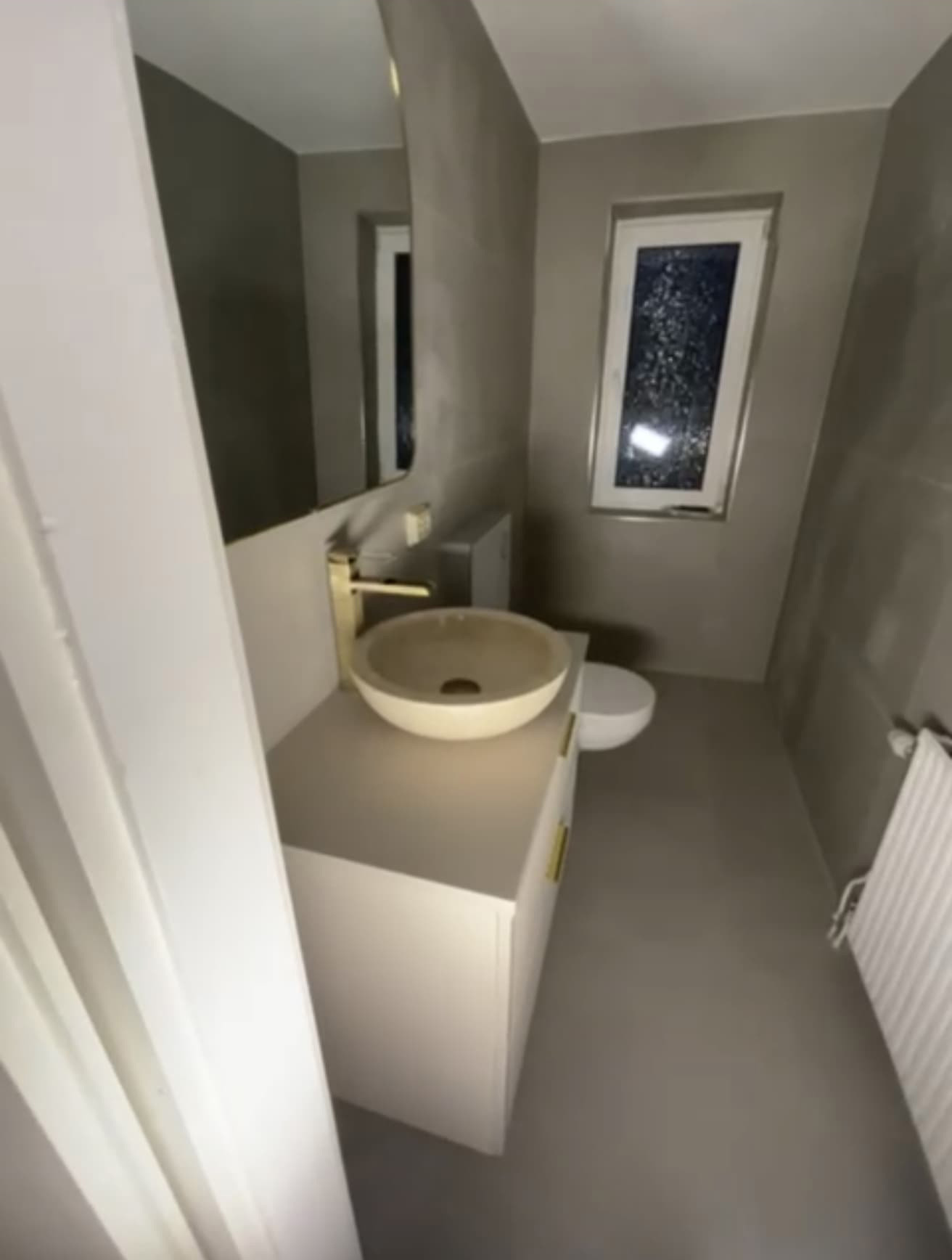 Modernes Bad mit beigem Waschtisch, rundem Waschbecken und schmalem Fenster.