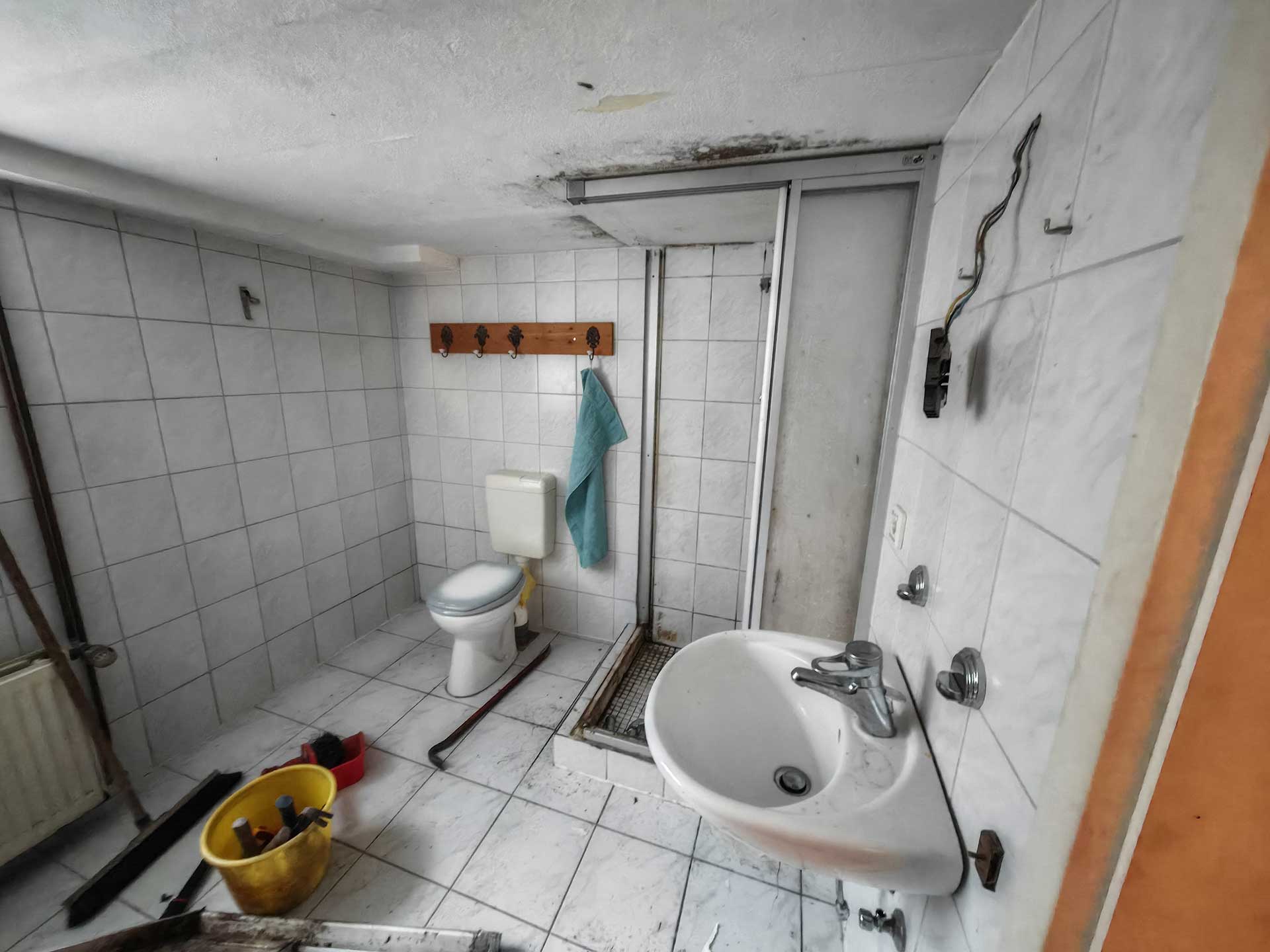 Ein schlichtes, altes Badezimmer mit weißen Fliesen und einfacher Ausstattung.