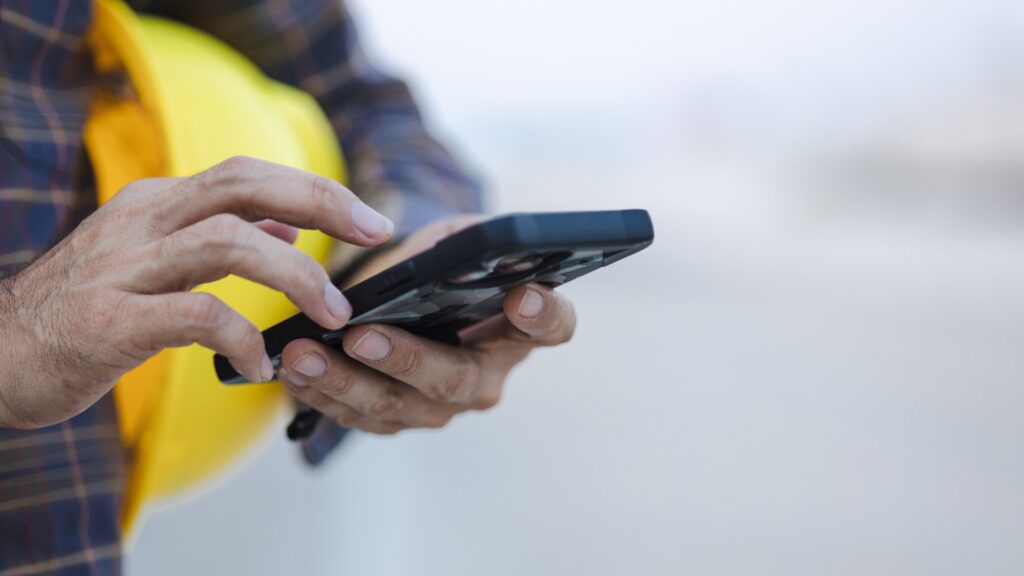 Bauarbeiter mit Touchscreen-Smartphone auf der Baustelle
